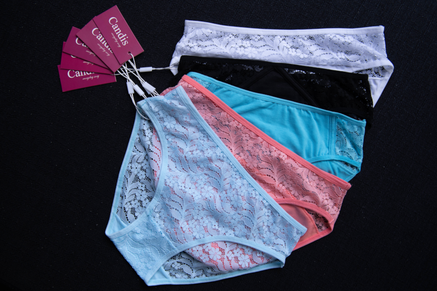 Four pairs of Candis-brand underwear in white, black, pink, and blue, displayed on a black background with tags visible.